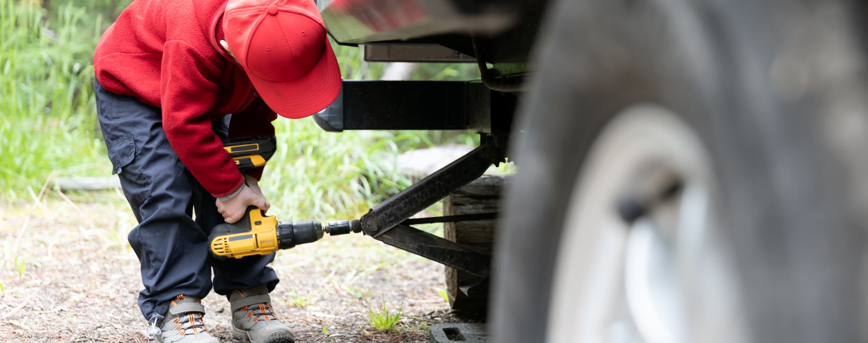 Child using drill to raise or lower a jack