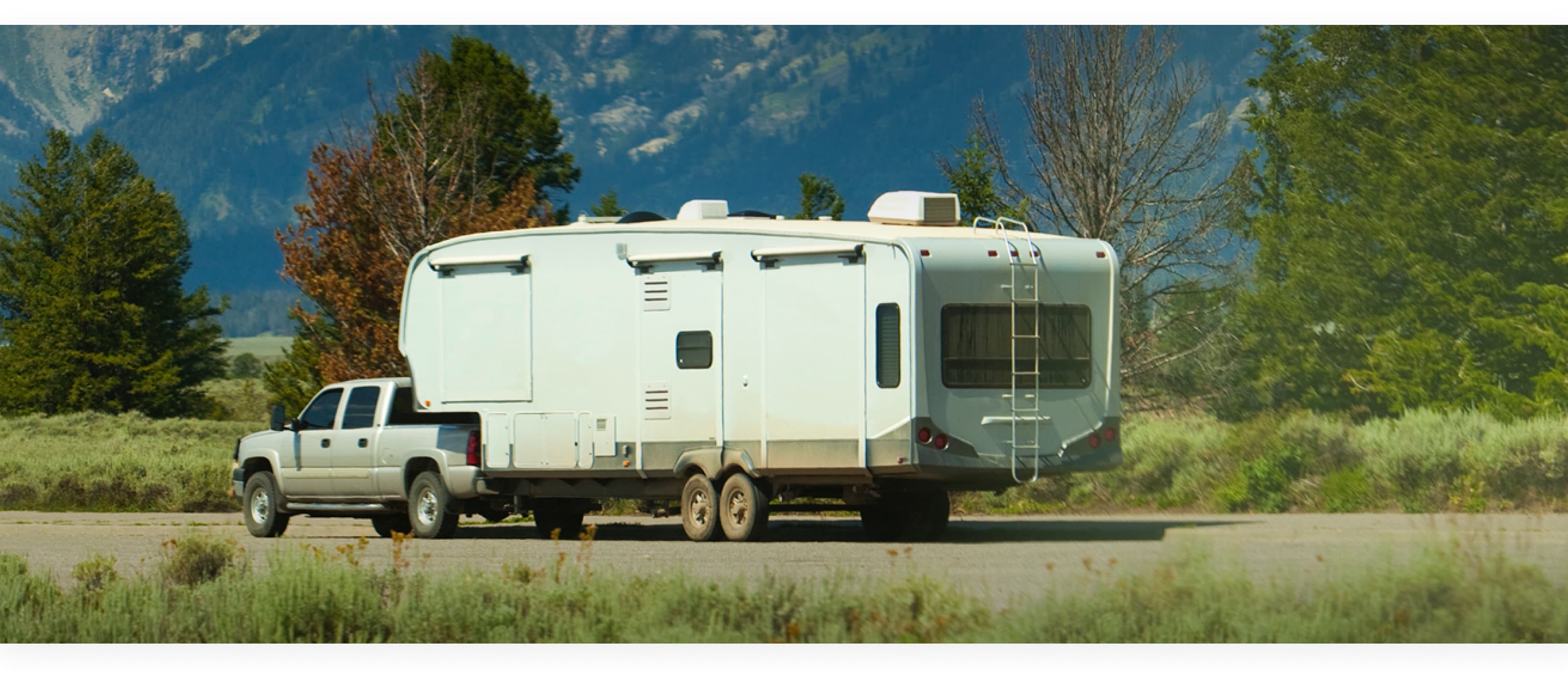 A truck towing a camper trailer on a mountain road