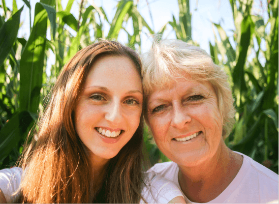 Smiling mother and daughter taking a selfie in a corn field